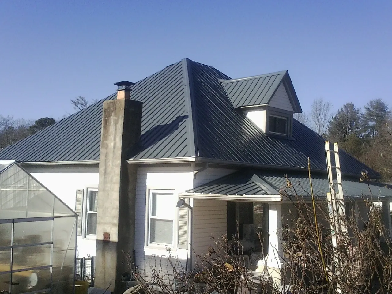 Dark blue standing seam metal roof on a white farmhouse with dormer — Slate & Tile Roof Repair by Roofing Brothers in Clementon