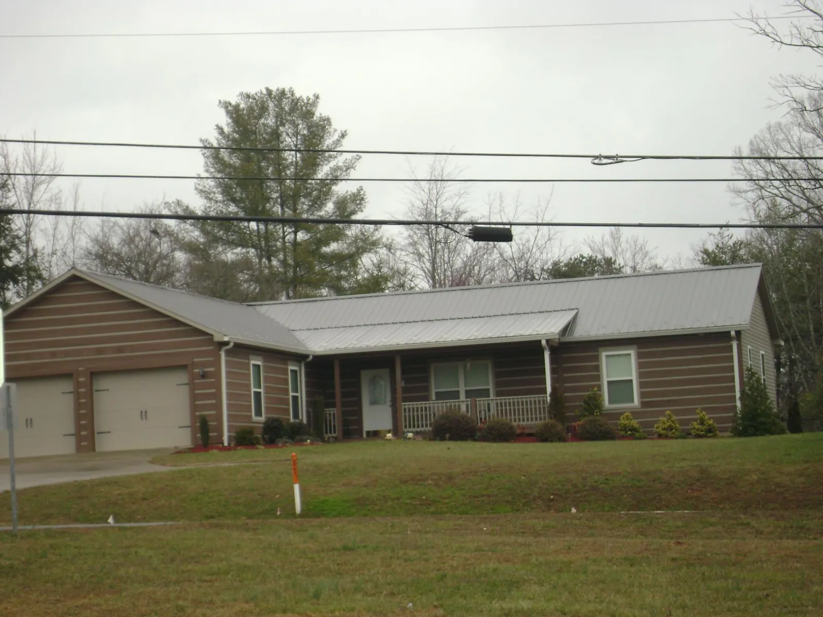 Gray metal roof on a log sided ranch home with a front porch in Clementon