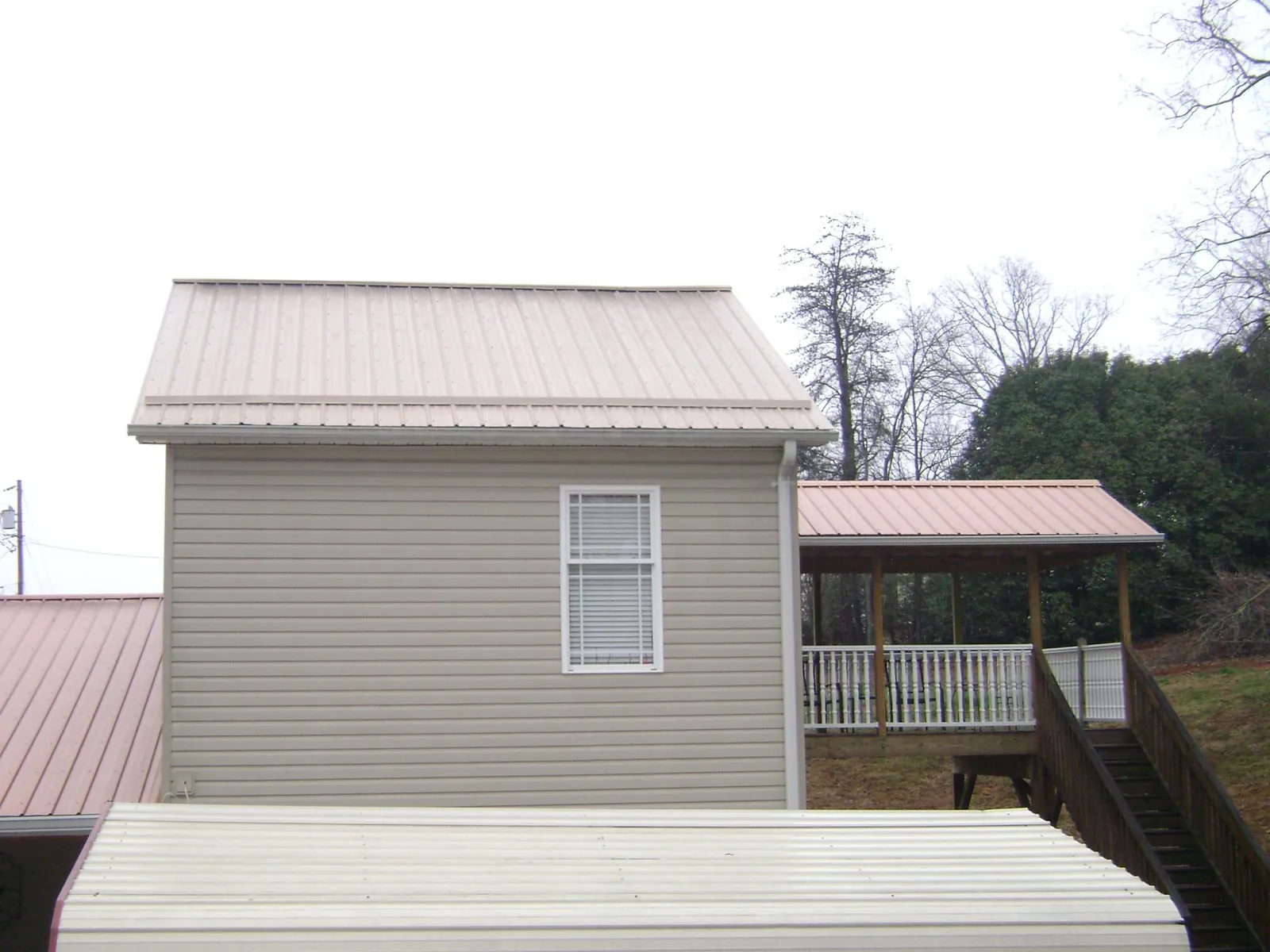 Tan metal roofs on a two story addition and attached porch, from a Roof Replacement job in Clementon