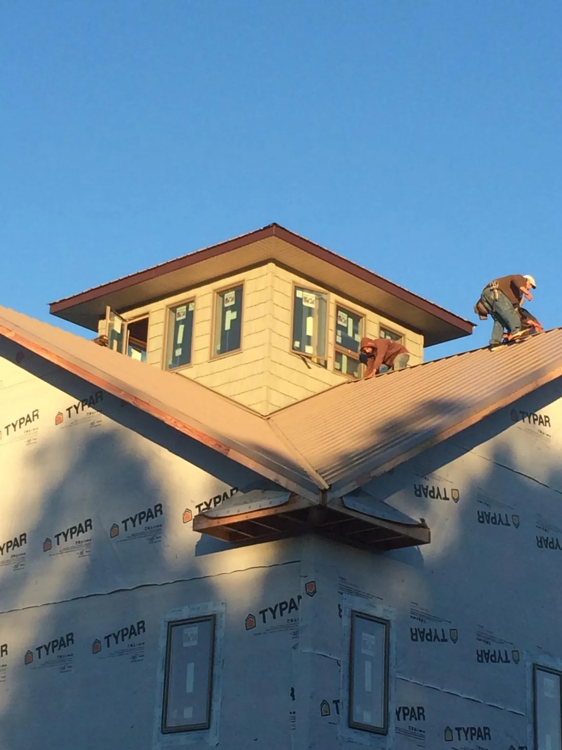 Roofers working around a rooftop cupola on a new metal roof at sunset — Roof Waterproofing in Clementon by Roofing Brothers